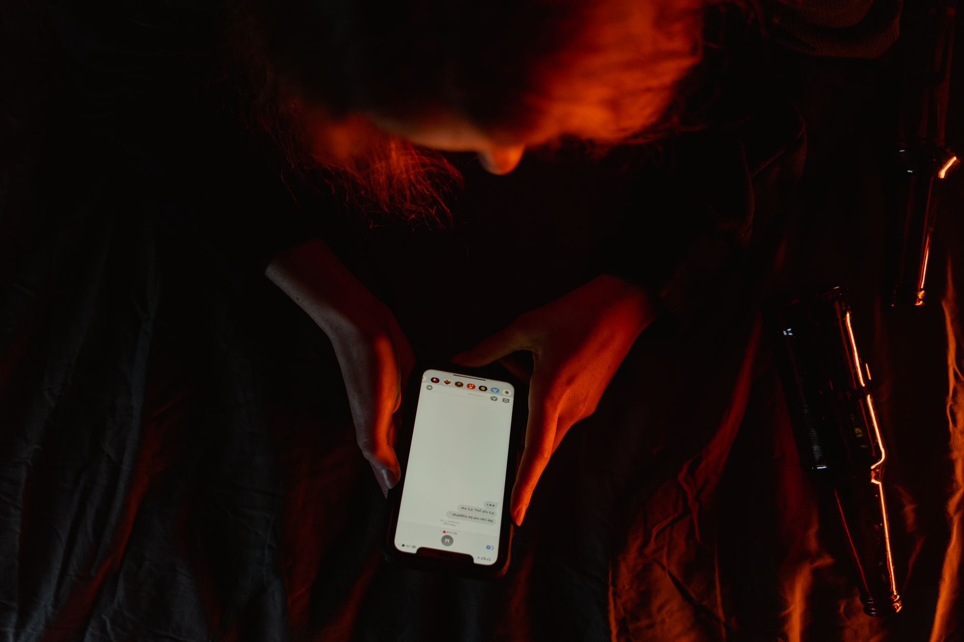 Pessoa deitada no sofá mexendo no celular à noite, representando o horário de pico do consumo de ofertas